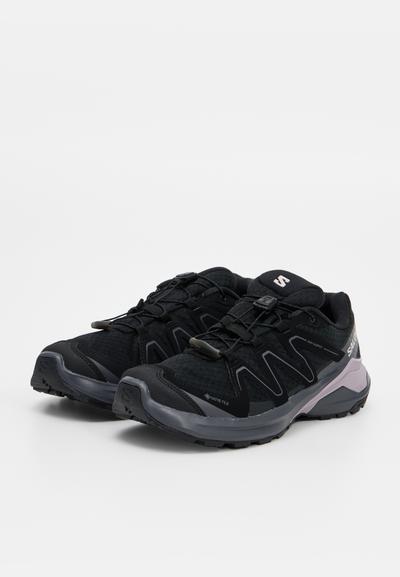 Paire de chaussures de randonnée Salomon Gore-Tex noires avec système de laçage rapide et semelles robustes, présentées sur fond blanc.