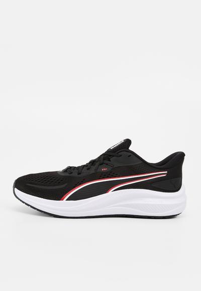 Chaussure de course noire et blanche avec des détails de rayures rouges et blanches, empeigne en mesh, lacets et semelle coussinée, vue de côté sur fond uni.