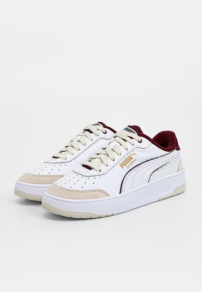 Baskets blanches avec accents en daim beige, embout perforé, doublure bordeaux et détails de logo dorés. Semelle épaisse en caoutchouc blanc.
