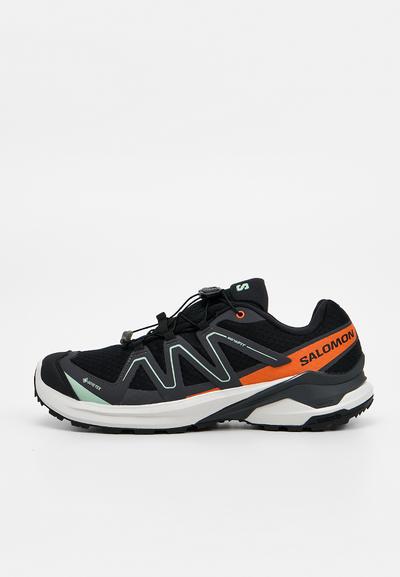 Chaussure de trail Salomon noire et orange avec semelle blanche, système de laçage rapide et tige en mesh respirant.