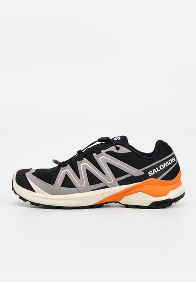 Chaussure de trail Salomon noire et grise avec des accents orange sur la semelle intermédiaire et un système de laçage rapide, vue de côté extérieur.