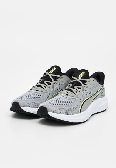 Paire de baskets de sport Puma grises avec des accents noirs, des semelles blanches, des dessus en mesh, des lacets noirs et des logos Puma jaunes sur la languette.