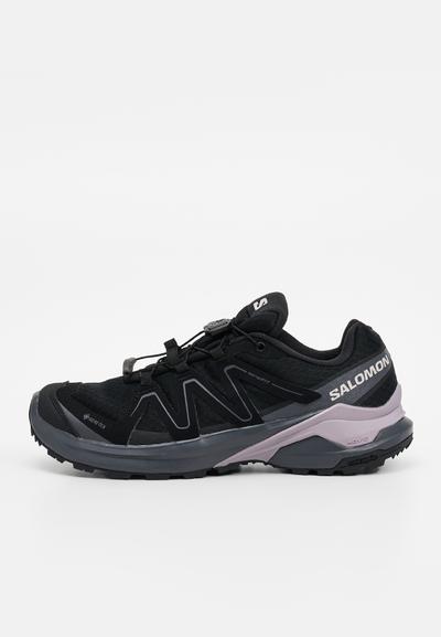 Chaussure de trail running Salomon noire et grise avec tissu Gore-Tex, système de laçage rapide et semelle texturée pour une adhérence en extérieur.