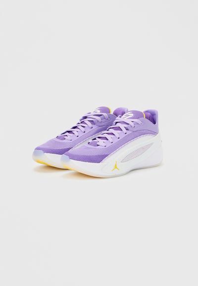 Paire de baskets basses de sport violettes et blanches avec dessus en mesh, lacets et accents jaunes sur un fond uni.
