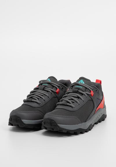 Chaussures de randonnée noires et grises avec tissu en maille, semelles en caoutchouc, accents rouges contrastés et détails logo bleus. Dotées de lacets traditionnels.