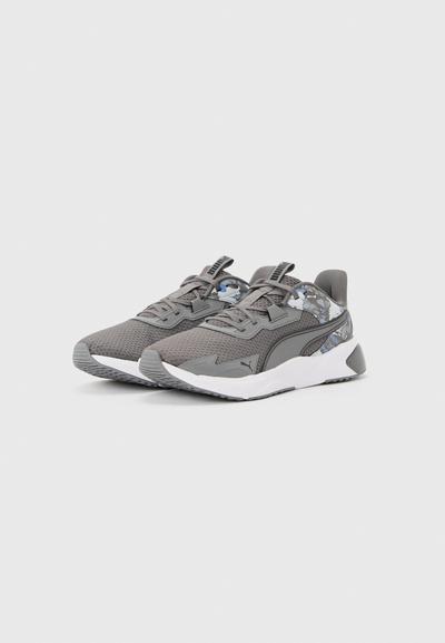 Paire de baskets de sport grises avec dessus en mesh, accents à motif camouflage, et semelle blanche, positionnées de biais sur un fond neutre.