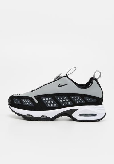 Baskets Nike grises et noires avec semelle blanche, languettes de traction et amorti à air visible, vues de profil sur un fond uni.