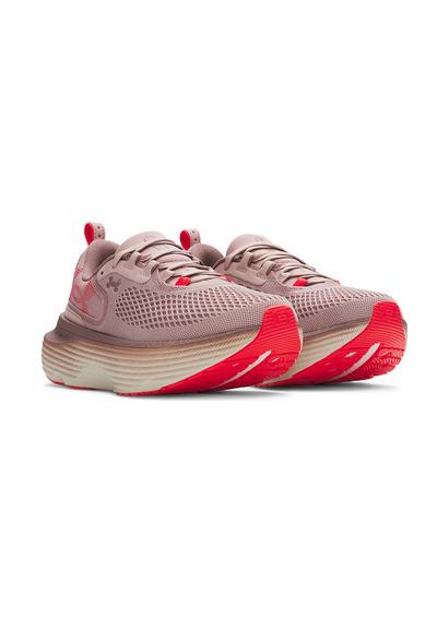 Des chaussures de course avec une tige en maille légère de couleur rose clair, des accents rouges, et une semelle texturée présentant des rayures blanches contrastées.